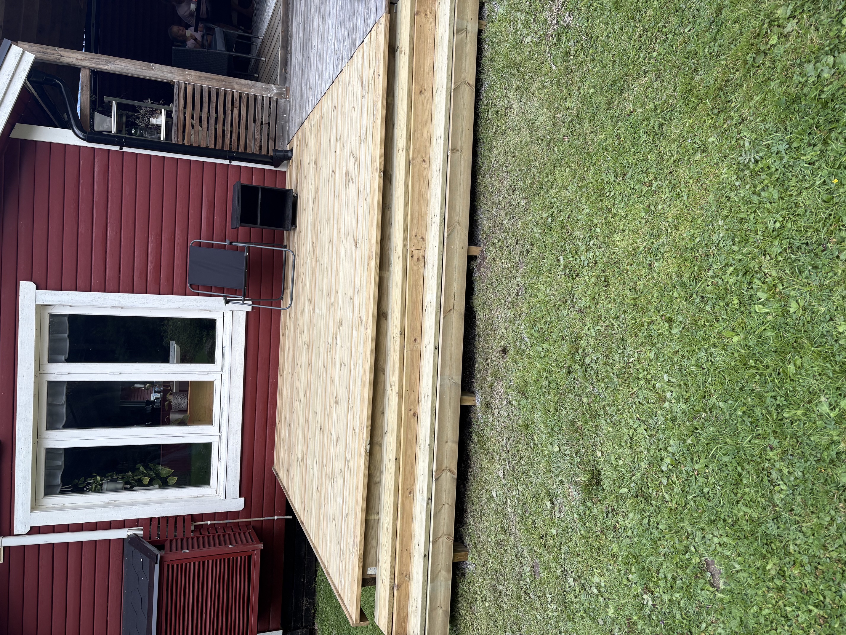 New wooden deck built beside a red house